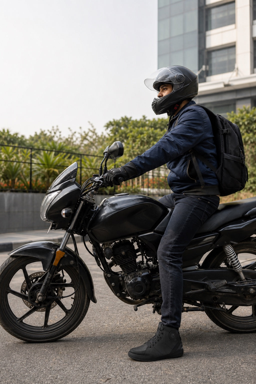 Indian commuter wearing ankle-height motorcycle footwear while stopped on a motorcycle near an office